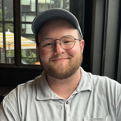 Elliot Schorr, wearing a blue polo and gray ballcap, smiling at the camera.